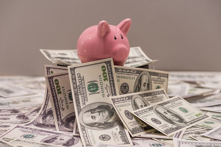 Piggy bank on top of money concept image for allocating budget for technology upgrade Piggy bank on top of money concept image for allocating budget for technology upgrade